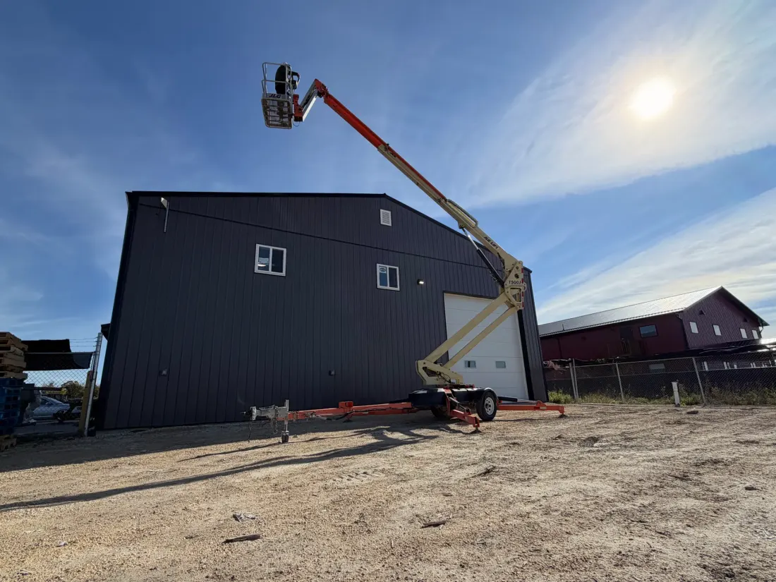 A towable boom lift reaching above the roofline of a building