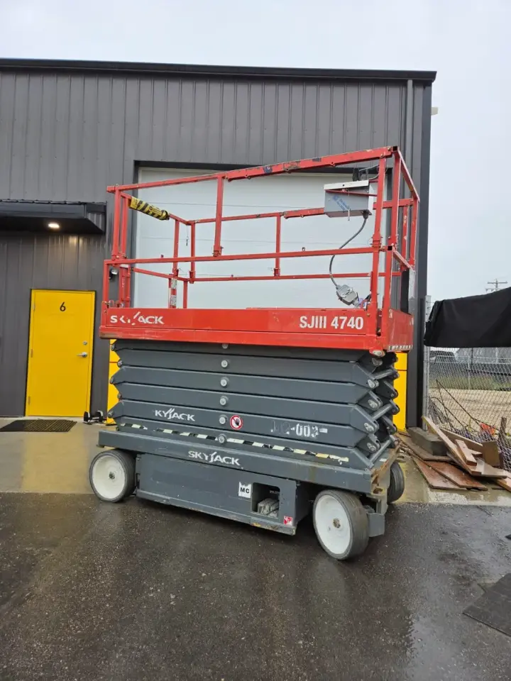 Red Skyjack electric scissor lift from the side, platform lowered